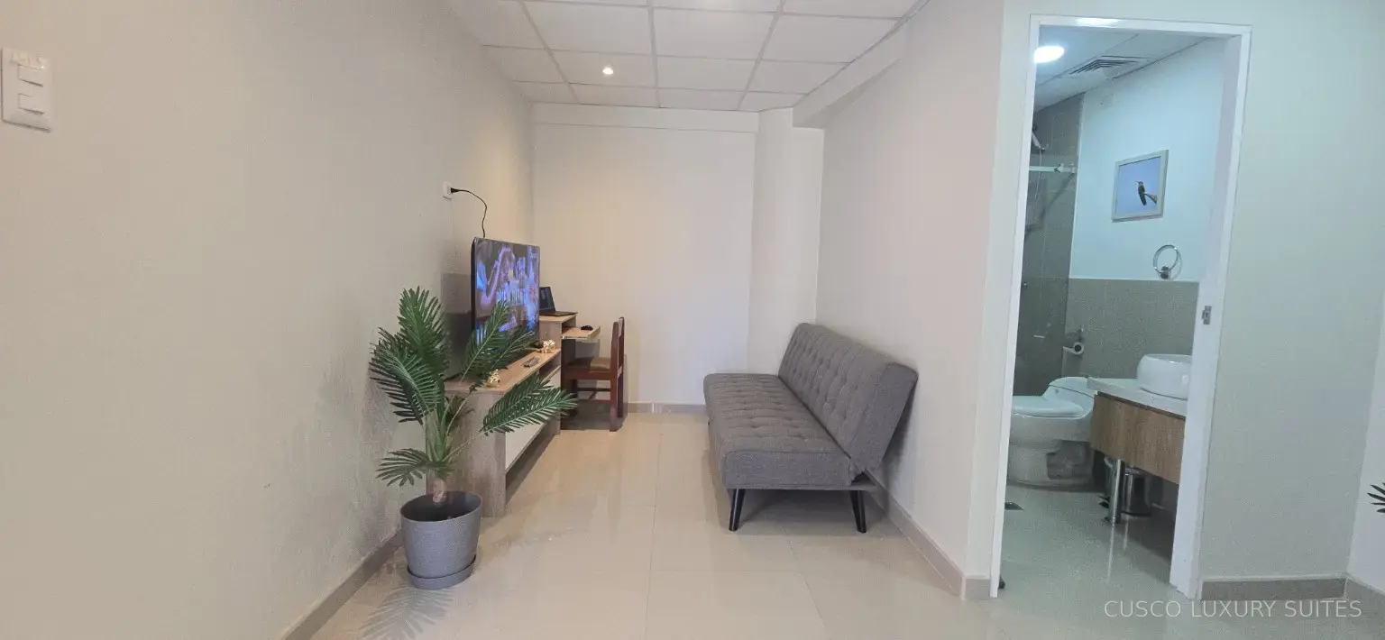 Private living area with sofa, Smart TV and adjoining bathroom in AYLLU SUITE