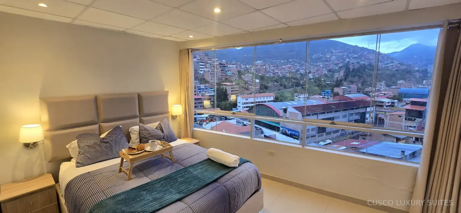 AYLLU SUITE primary bedroom with a wall of windows overlooking Cusco