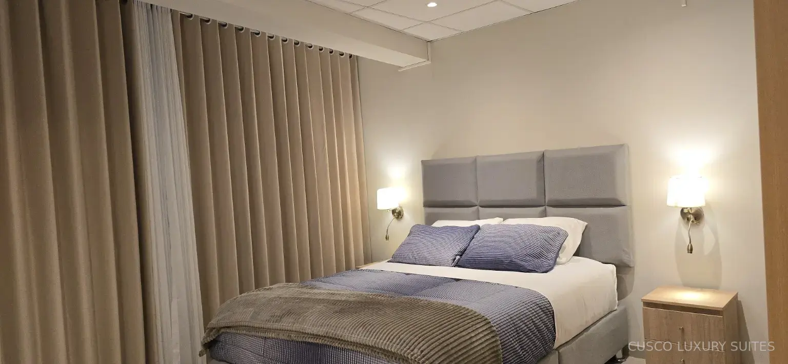 INTI SUITE queen bedroom with warm bedside lighting and blackout curtains