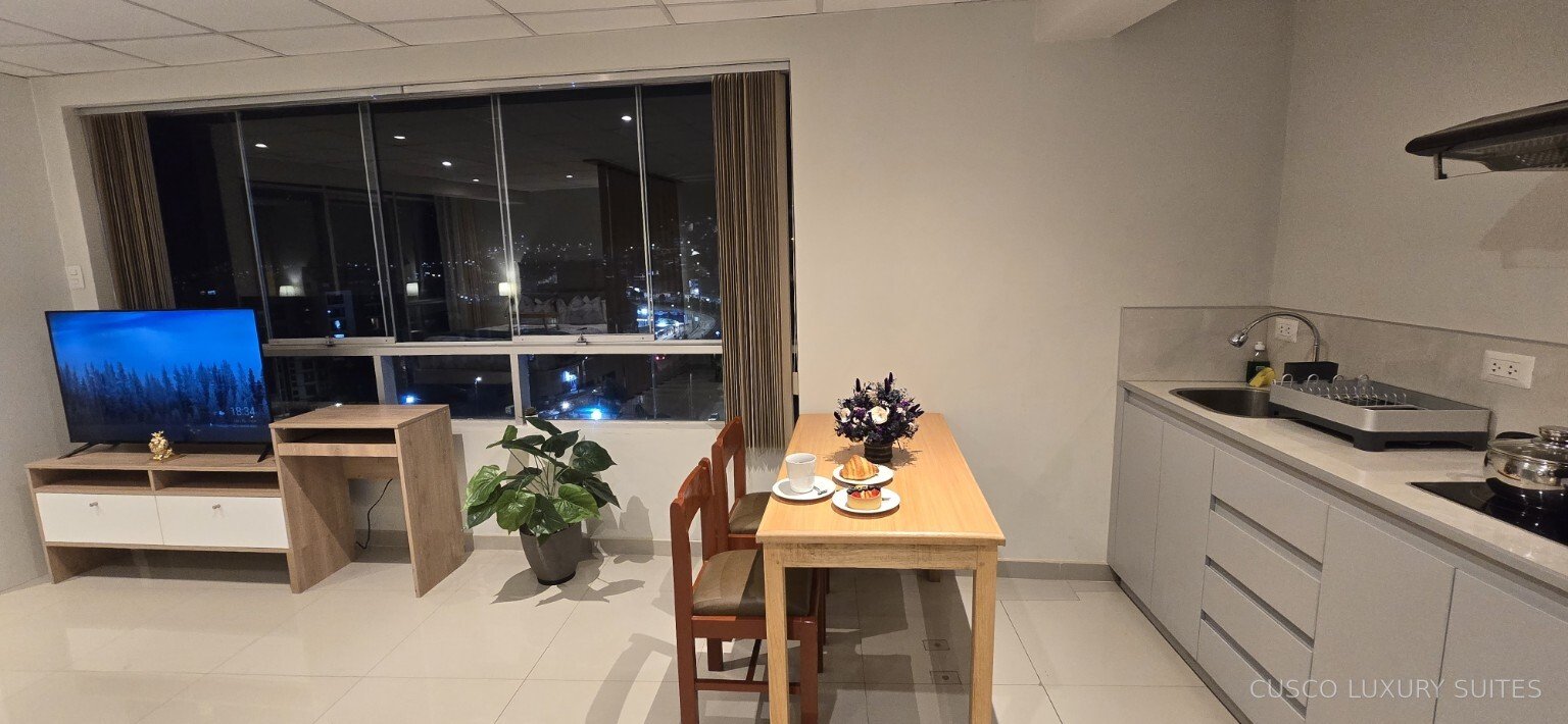 SUMAQ SUITE dining area, kitchen and Smart TV beside the night view of Cusco
